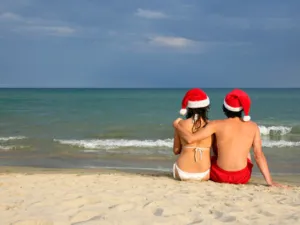 2 Personen mit Weihnachtsm&uuml;tzen am Strand